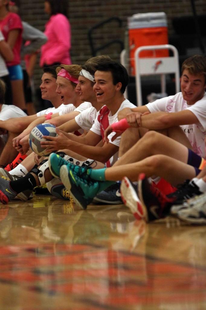 The soccer players cheer for their teammates who are playing in the volleyball game to raise money for cancer