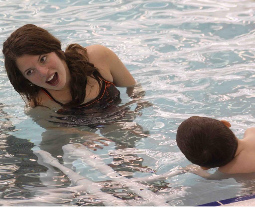 Tilted sideways. Senior Alexis Kontorousis teaches a toddler how to turn his head and come up for air while in the pool.