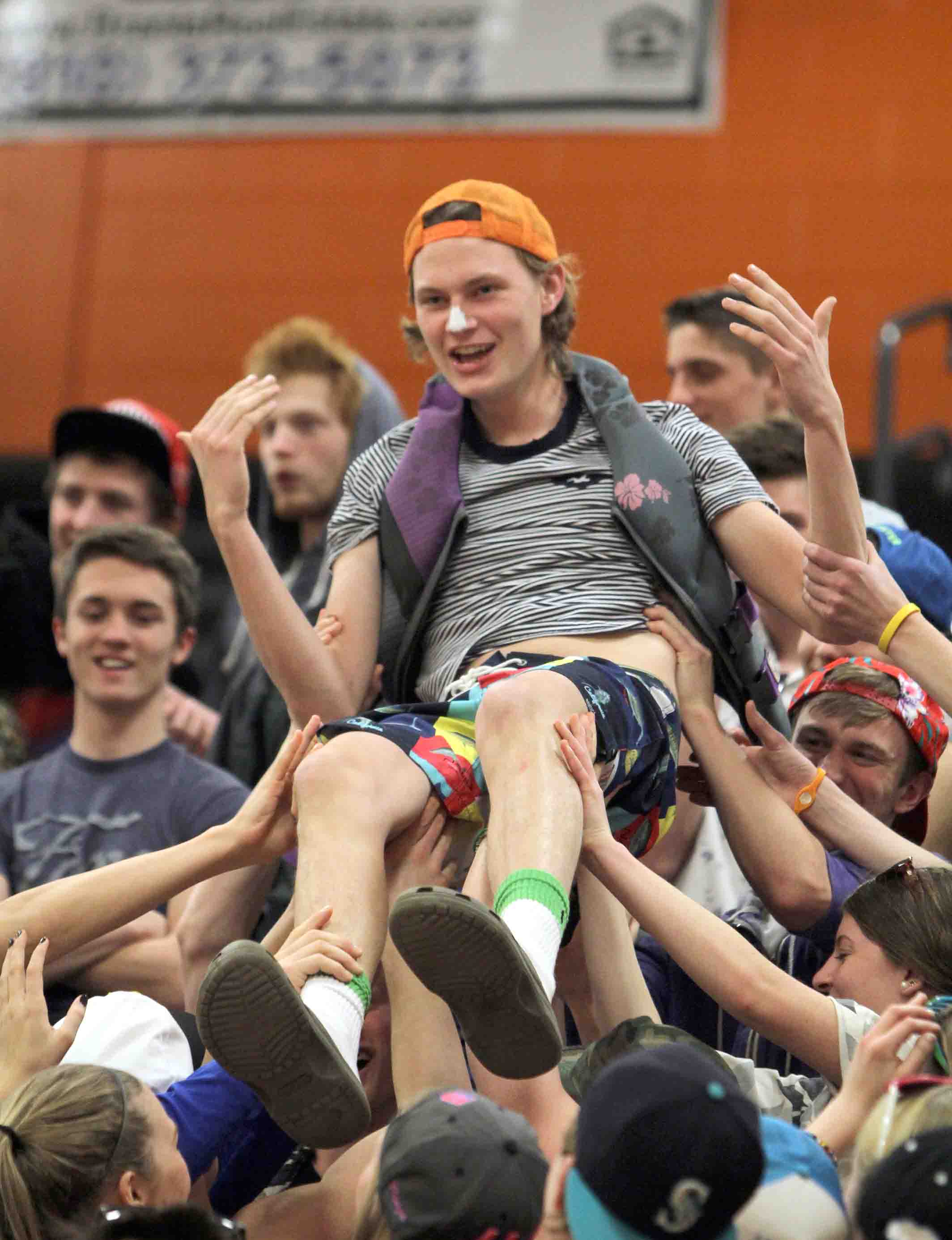 Surfs Up. Crowd surfing through the senior side of the student section during halftime of the boys basketball game against Lapeer East on Jan. 24, senior Alex Fulton is carried upward over the crowd. “I started crowd surfing over the seniors because we had to show up the juniors,” Fulton said. “The theme that night was beach night and this game was the most fun because of the huge crowd we had.” 