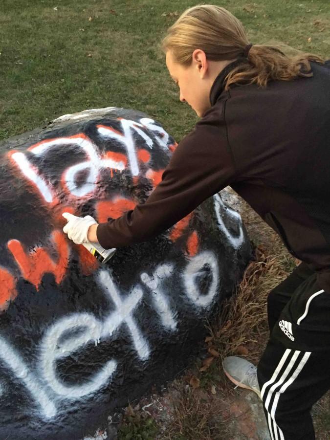 Senior Bri Costigan goes over the white spray paint with orange, declaring the varsity girls swim and dive teams 12 years of swim and dive champions. 