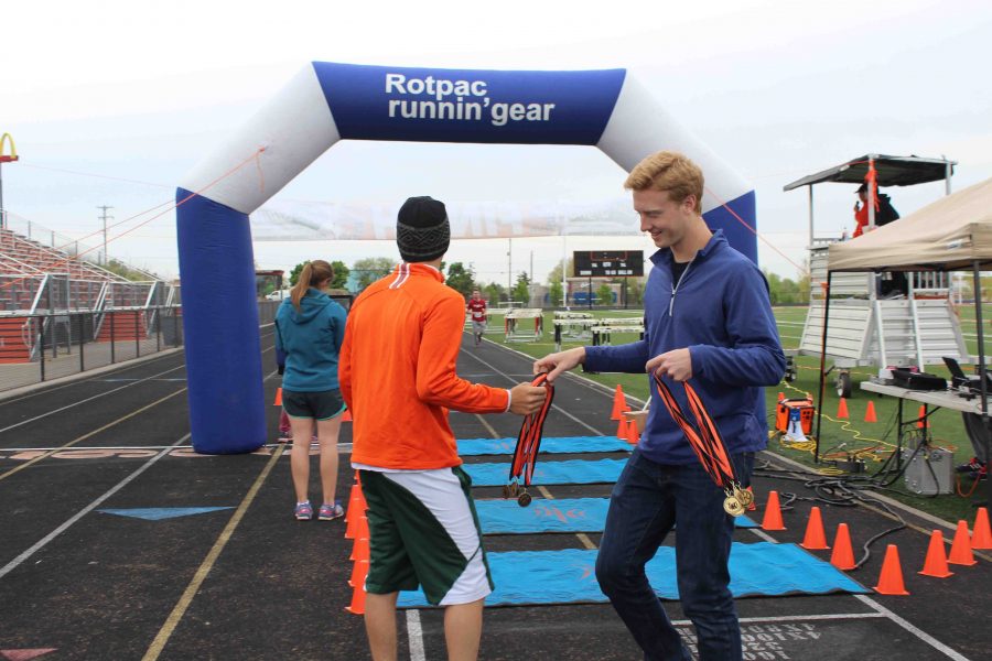 At the Tiger Run, senior Jon Leaske passes out medals to the finishing runners. I was helping out for NHS, Leaske said. It was fun to see the runners coming across and cheering on the people who were running because it made them happy. The little kids who ran across were funny because they were running hard and when they crossed the finish line, they were amazed to get a medal and felt really good about themselves. 
