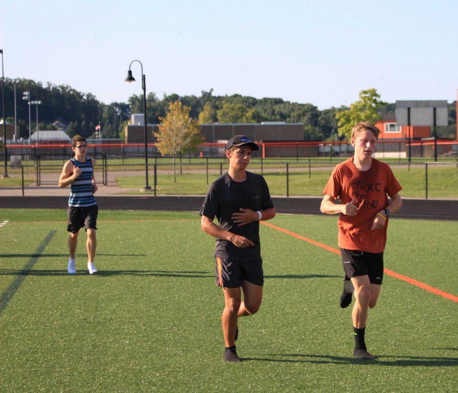Seniors Dominic DiMambro and Andrew Bond run up and down the field. During their routine, they check their times with the clock on their watches.