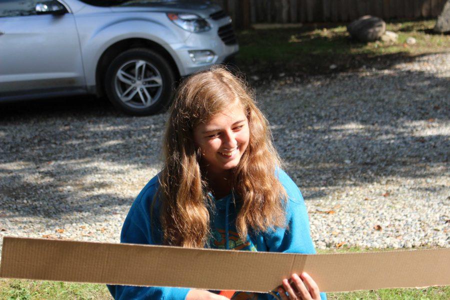 Sophomore Kara Piwowarczyk cuts pieces of cardboard for the siding on the UP house for the sophomore homecoming float on Oct. 2.
