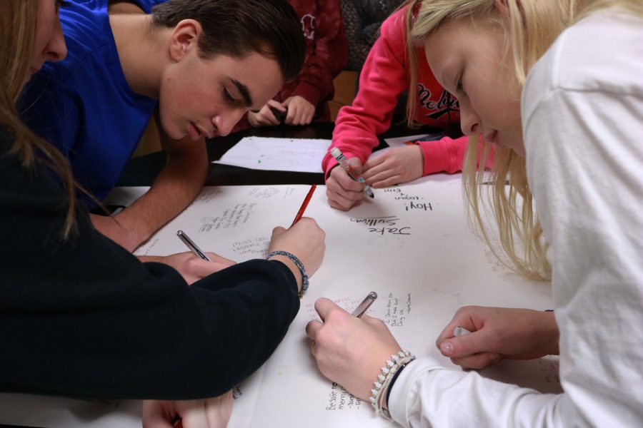 Freshmen Ricky Giltrop and Bailey Parker write a message on a holiday card for Stephanie Roberts. Roberts is currently deployed in Germany, but prior to her service, she worked as a history teacher at AGS Middle School.