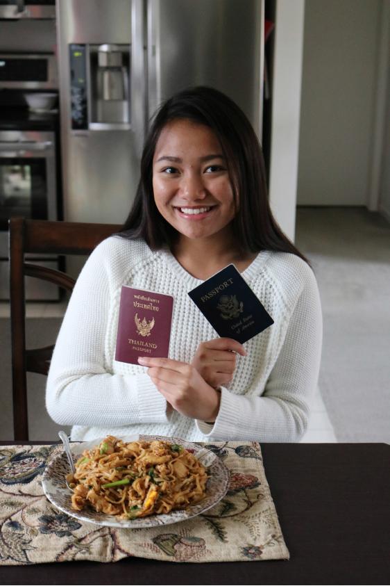 Sophomore Dow Kaenpracha poses with each of her passports, one from Thailand and the other from the U.S.. Also with her, is her aunts homemade Thai food which replicates the food she would have in Thailand.
