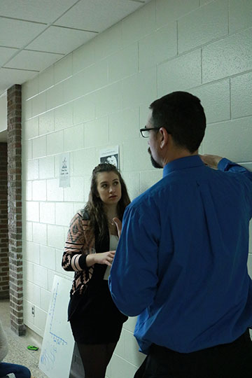 1B class working on a lab about distance and Displacement. Lilly McKee, freshman, asks Jason Kasak how to do more for the lab. 