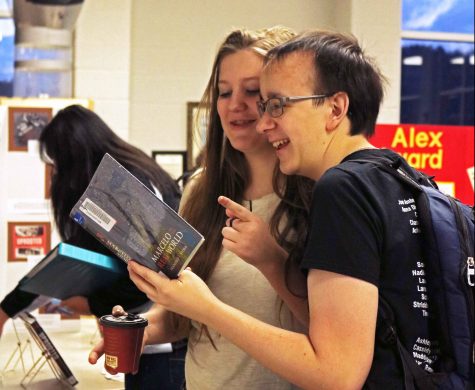Juniors Joe Amberg and  Olivia Blumenschein observe the American Library Association award winning books displayed in the media center  this morning. In addition to the books, a coffee bar was offered to participants.