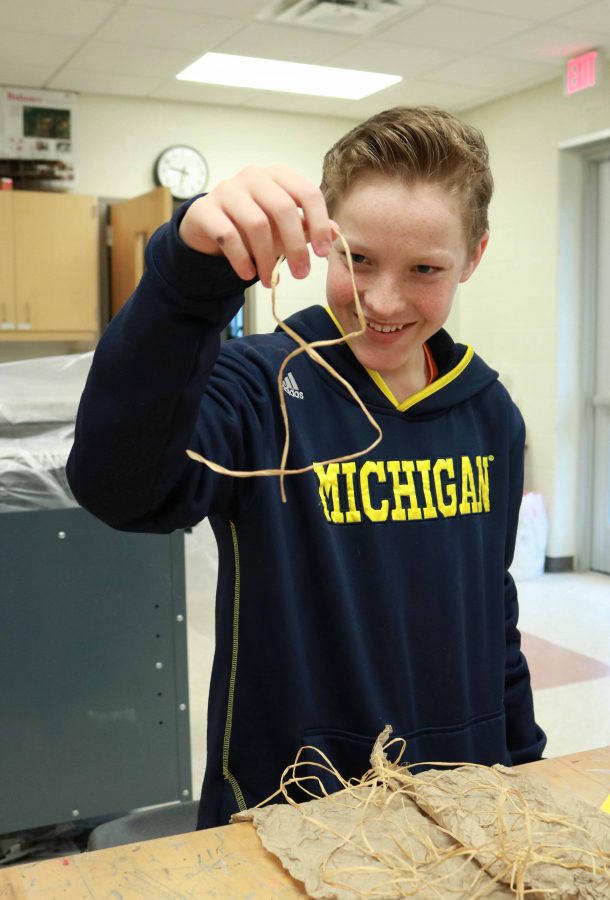Finishing up his project, freshman Mitchel Sheer pulls up strands he missed gluing down.