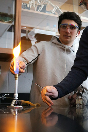 Beginning his lab, senior Thomas Kemp and his group test chemicals by lighting them on fire.