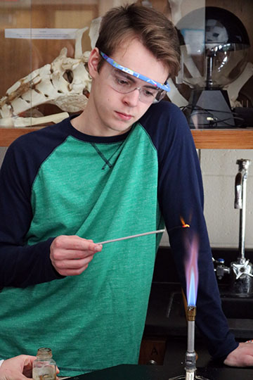 Burning different chemicals on a stick senior, Colin OConnor burns their groups first chemical. 