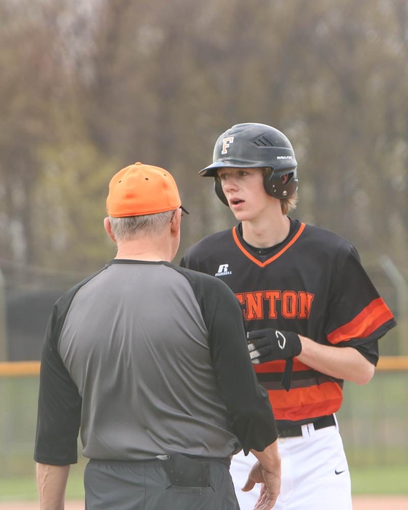 Junior Nolan Lawrence discusses his hit and the game with the first base coach.  The varsity team played Lake Fenton on Apr. 26 and won 18-6.