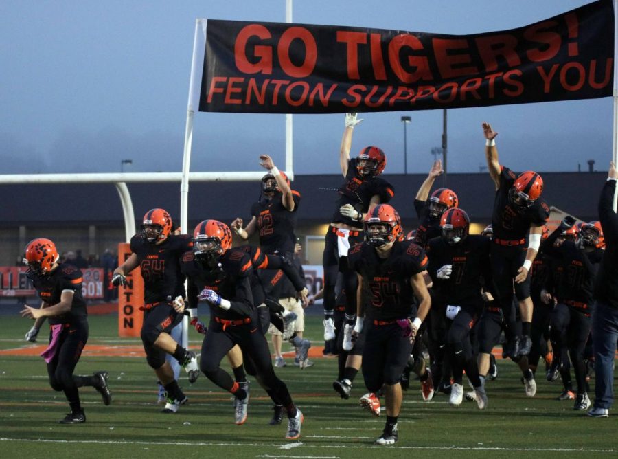 Just minutes before the start of the 2017 Homecoming football game, the varsity football team gets riled up by their head coach. After running between cheerleaders and youth football players, the boys leap to touch the Fenton Supports You! banner. 