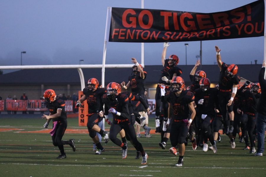 The+boys+varsity+football+team+starts+off+the+game+by+entering+under+the+banner.+