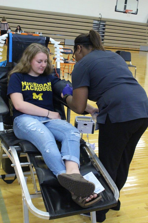 During the first NHS blood drive, junior Kyle Bliss watches as a nurse preps her arm to give blood. 
