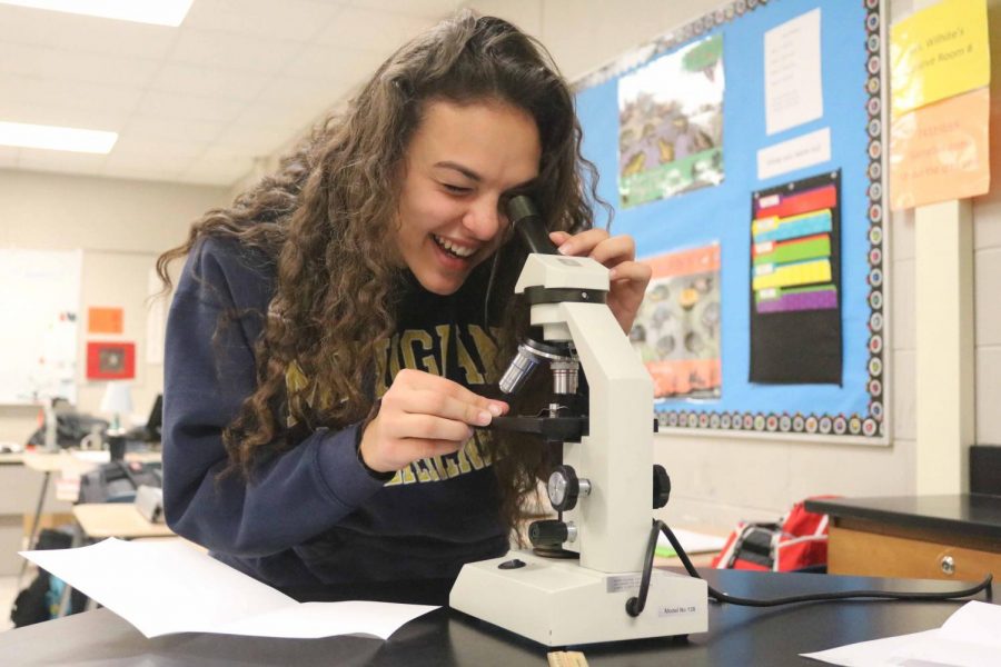 Sophomore Regina Pauly smiles as she is looking at the living bacteria underneath the microscope. Kimberly Wilhites biology class looked at the pond water and drew the living bacteria. 