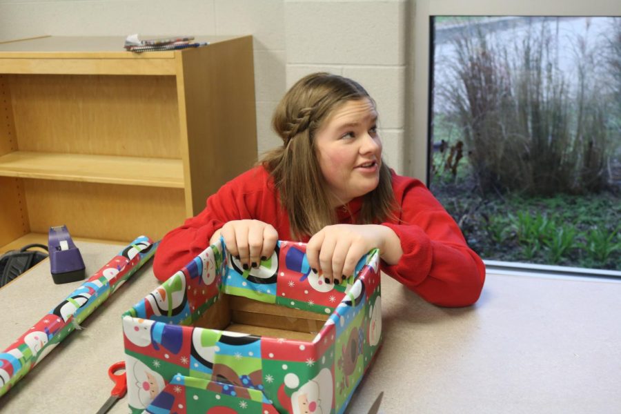 As a member of Key Club, junior Natalie Thomas wraps boxes for the upcoming food drive. 