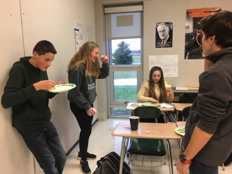 On their last day before Christmas break, juniors Jack Killian, Kyle Bliss, Julia Stocker and Parker Bundy eat food that was brought in for their IB history party. While enjoying the food that was brought in, the students were also assigned to create a mural documenting Latin American Independence.