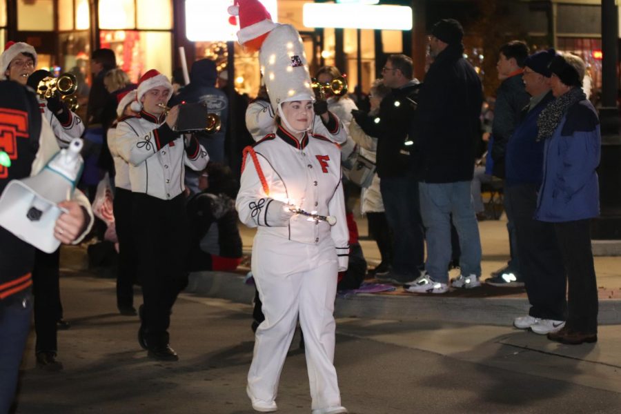 Guiding  the marching band down the streets of Fenton, junior Drum Major Emily Hayes leads the band in their holiday songs during the Jingle Feast. 