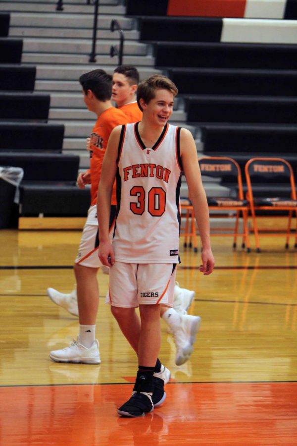 Warming up for the freshman basketball game against Clio, freshman Carter Frost smiles at his friends and family in the crowd. On Thursday January 30, the freshman beat Clio 64-23.