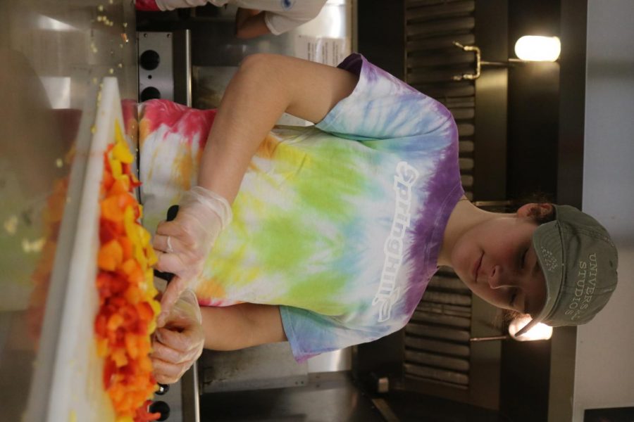With her army green hat on, junior Jamie Elrod helps the soup kitchen staff by slicing vegetables. The key club members volunteered at the Soup Kitchen in Flint on Saturday the 26. 