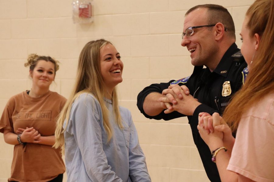 Smiling as a local police officer uses her as a demo, junior Natalie Brown helps demonstrate in front of her class. Mrs Moores 2A fitness class got taught self defense in the phase of an emergency. 