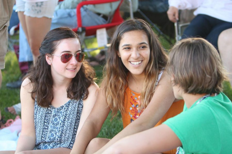 Talking with friends, junior Karrena Mansour listens to an orchestra concert behind the Fenton community center on June 14. Students watched and performed in the Fenton Community Orchestra concert in the part at the start of summer. 