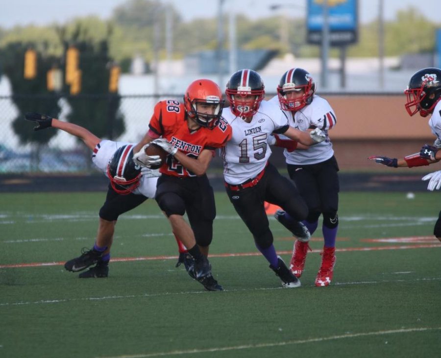 While carrying the football, freshman Trey Hale attempts to break through the defensive line. The Fenton freshman team defeated their rivals: the Linden eagles.
