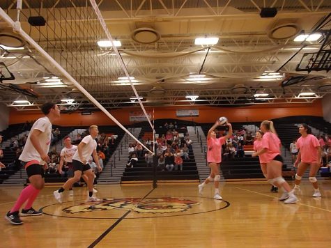 While junior Sydney Acho sets up the ball to middle hitter senior Erin Carter, the boys varsity soccer team watches on. The girls volleyball and boys soccer programs participated in Volley-4-a-cure fundraiser for the Negley family.