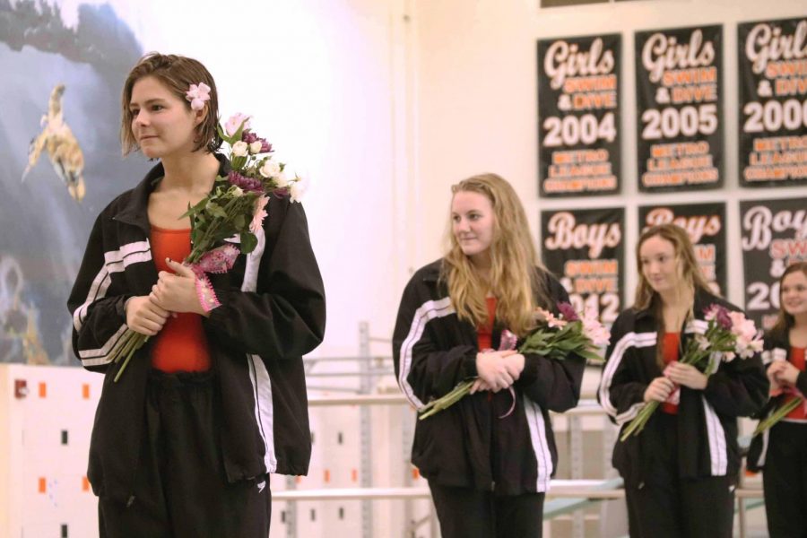 With flowers in their hands, the Fenton High girls swim team celebrates senior night on Oct. 25, 2018. The senior girls did their yearly tradition by jumping into the pool after their names are called. 
