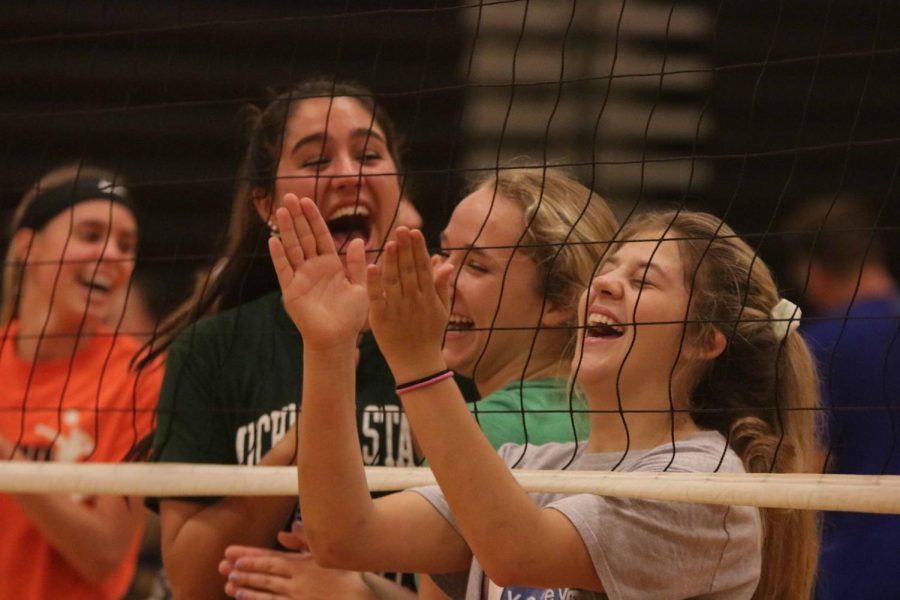 While watching the parents, junior Meg Wolosonovich laughs at the parents as they warm-up for Family Fun Night.  On Oct. 3, the volleyball program and parents played each other in a game of volleyball.
