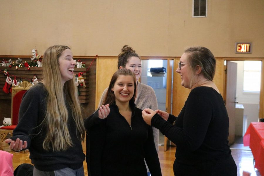 After her friend cracks a joke, junior Reagan Lange laughs along with her friends from Key Club. Students from Key Club volunteered to set up for the Jingle Fest at the Community Center on Friday Dec. 3.