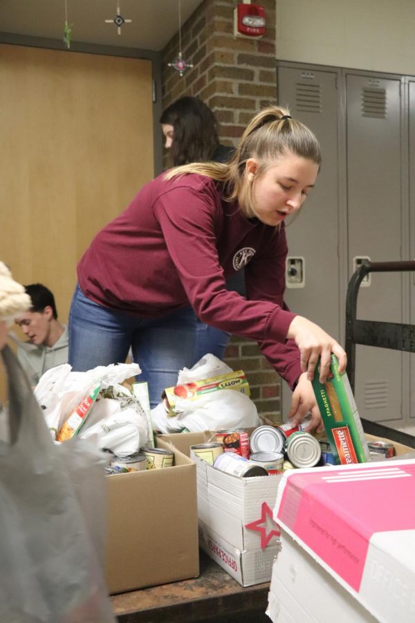 Senior Maci Best puts food on a cart during the Key Club food drive pick-up. On Dec. 17, Key Club members picked up food around the school that students brought in to their SRTs for the food drive. 