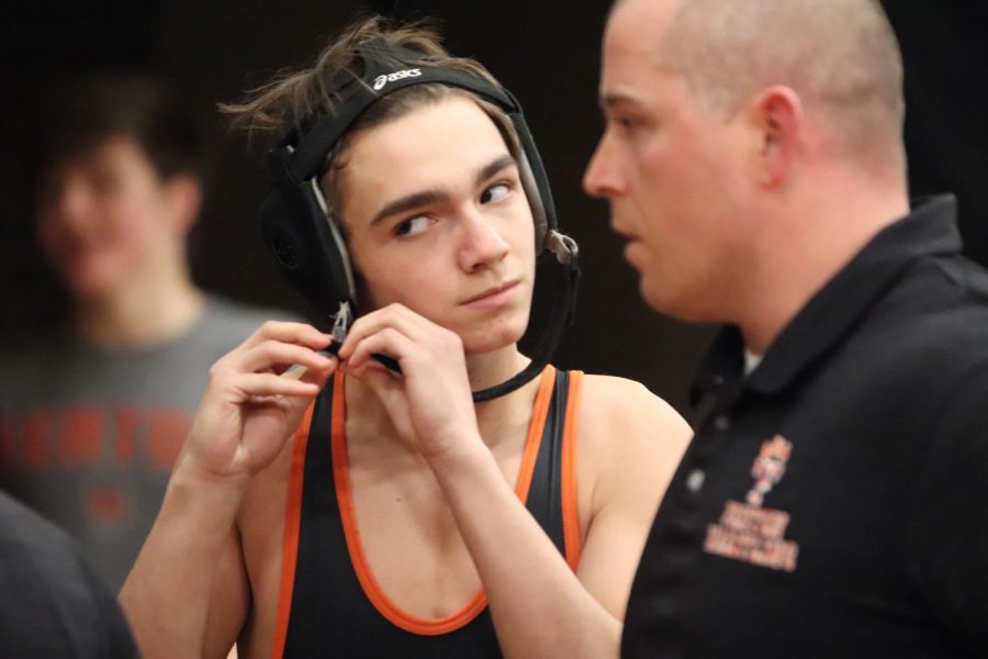 In preparation for his match against Holly, freshman Trey Hale puts on his headgear. Hale gets Fenton the point, giving his team a boost to their confidence.