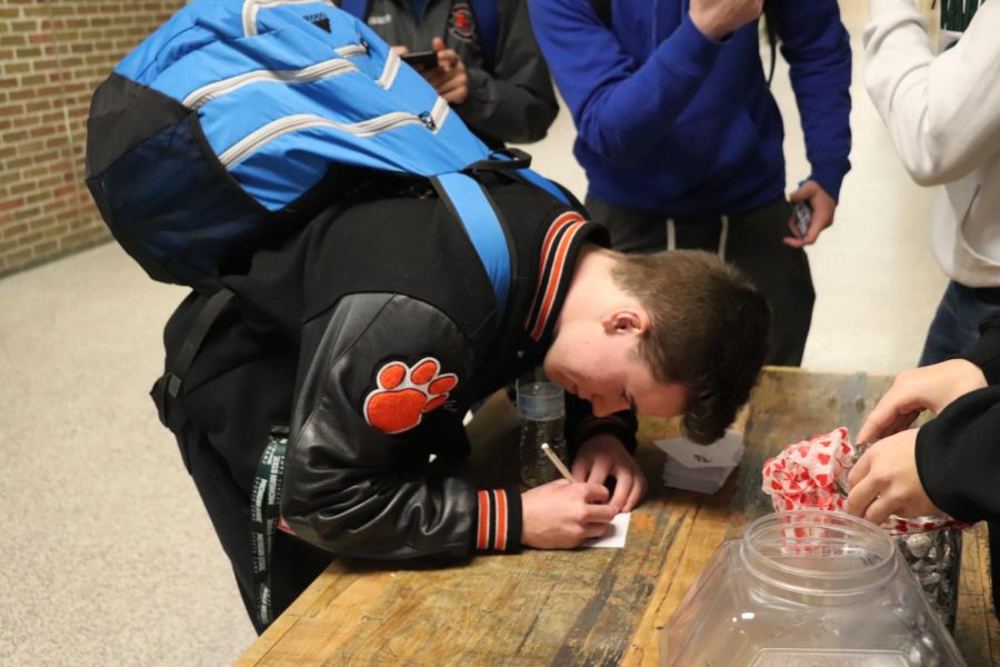Junior Brady Triola guesses the number of Hersheys Kisses in the jar. Yearbook staff administered a Valentines Day guessing game where students could guess how many candies were in the jar; the closest guess will win the jar.  