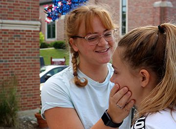 As the parade begins, senior Zoe Simmerman gives a child a temporary tattoo. Simmerman was volunteering with the Fenton United Methodist Church.