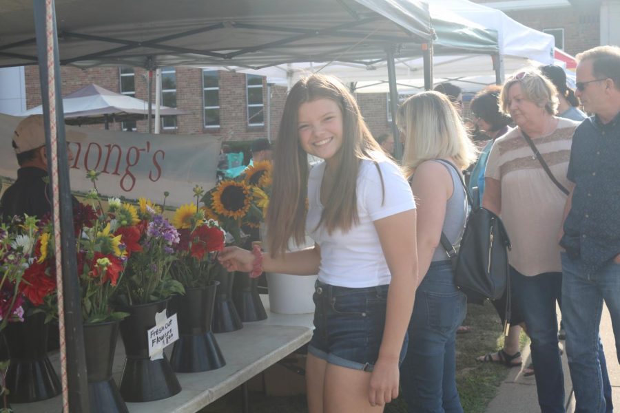 Abi Baran looks at flowers being sold at the Farmers Market on August 22nd. That night there was a concert in the park at the gazebo. 