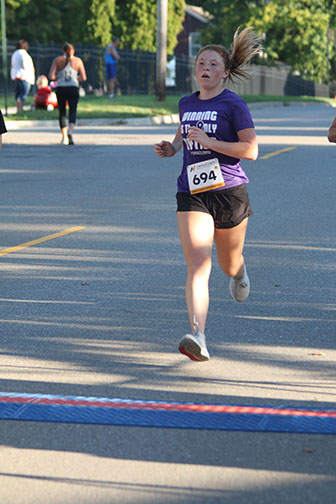 At the end of her 5k run, freshman Delaney Moon crosses the finish line. On 9/14/19 there was a 5k run/walk to kick off the 2019 Applefest!