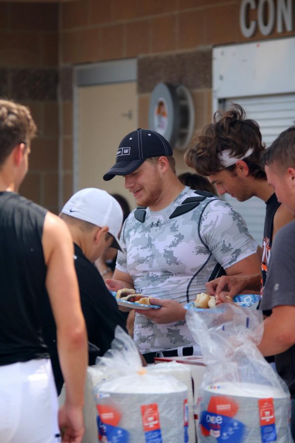 After+playing+in+a+scrimmage+senior+Zach+Shulz+goes+down+the+line+to+get+his+food+at+the+player+and+families+picnic.+On+Aug.+17+the+football+teams+scrimmaged+eachother+and+then+held+a+picnic.