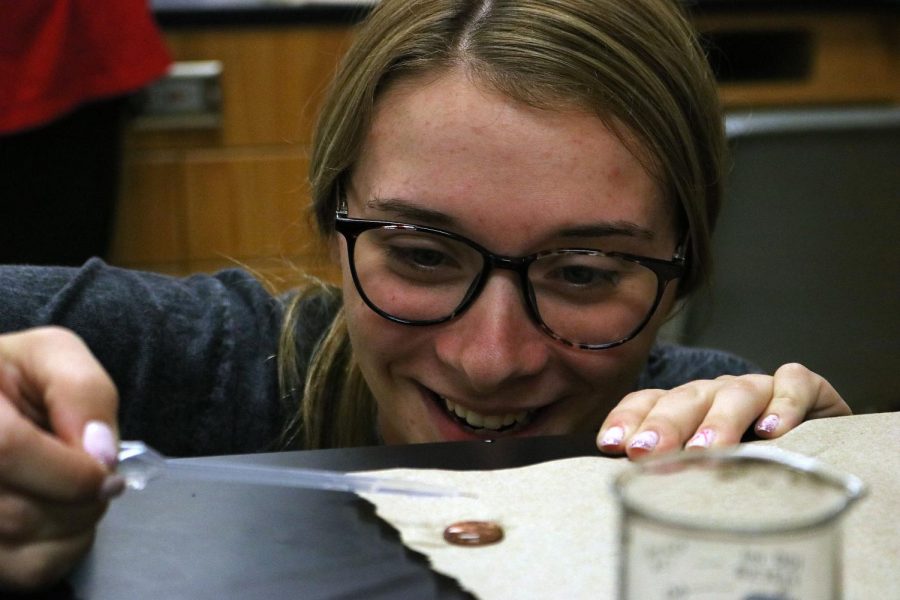Junior Emma Hartsell laughs as she counts how many drops of ethanol she can put on a penny. On Sept. 30, Chuck Miller had his classes perform a lab to test molecular stickiness. 