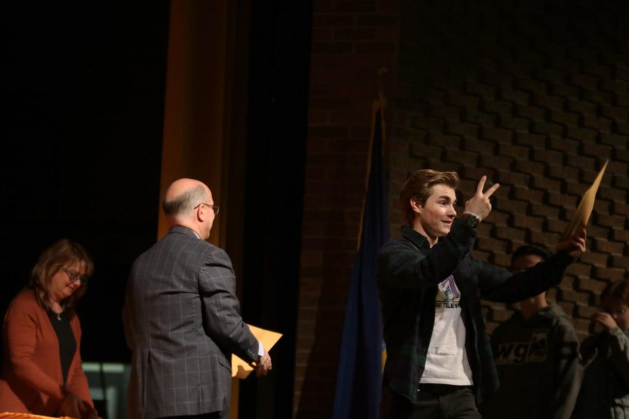 Senior Andrew Donar throws up a peace sign as he holds up his academic award . On Oct. 29, grades 10-12 received academic achievement awards.