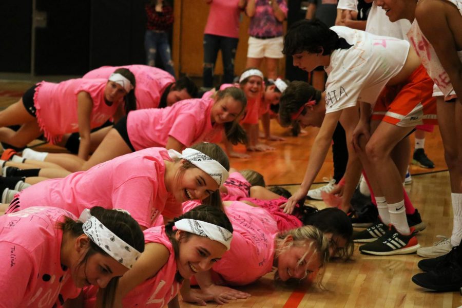 With support from the boys soccer teams, the girls volleyball teams do push ups. The two teams versed each other in a friendly game of volleyball on Oct. 10 to raise money for a Fenton student with cancer.