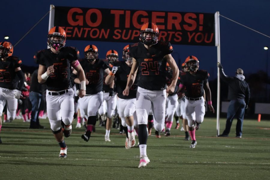 With+the+banner+behind+them%2C+the+varsity+football+team+runs+onto+the+field+to+face+Walled+Lake+Northern+High+school.+The+tigers+won+this+game+58-7+on+Oct.+25.