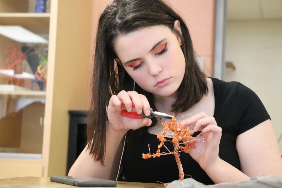 Junior Lilia Healey uses small movements and steller focus as she adds flowers to her bonsai tree. On Nov. 18 teacher Tracey Jambeck had her class create bonsai trees with materials they purchased using their grant money. 