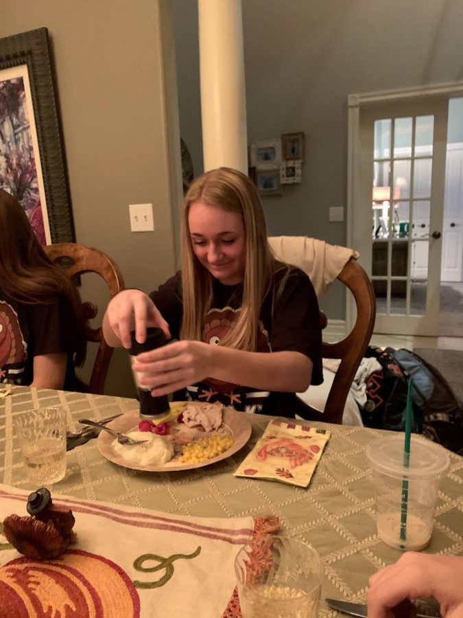 While+she+socializes+with+her+friends%2C+sophomore+Bella+Henson+salts+her+food.+Henson+and+seven+of+her+friends+attended+their+annual+Friendsgiving+this+year+on+Nov.+23.