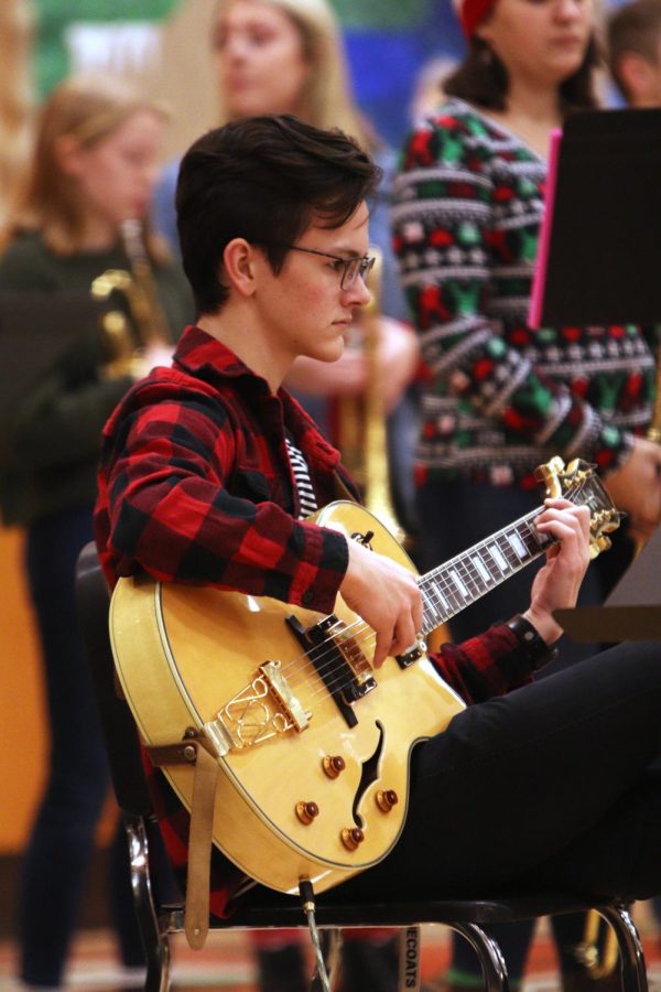 Waiting for students to take their seats, senior Cray Dumeah plays the bass guitar. The Jazz Band joined the Fenton Choirs for their annual holiday concert on Dec. 20.