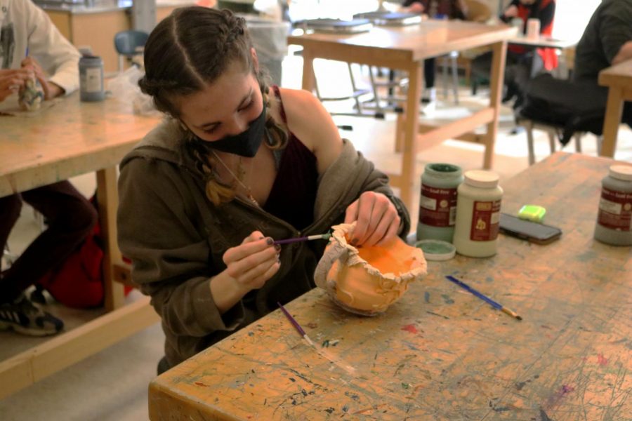Sophomore Emma Dubie focuses on painting her clay pot perfectly. 
