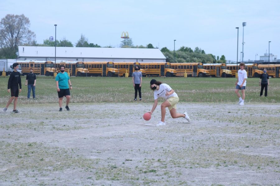 Roman Guerra rolls the kickball for the opposing team during gym class. 