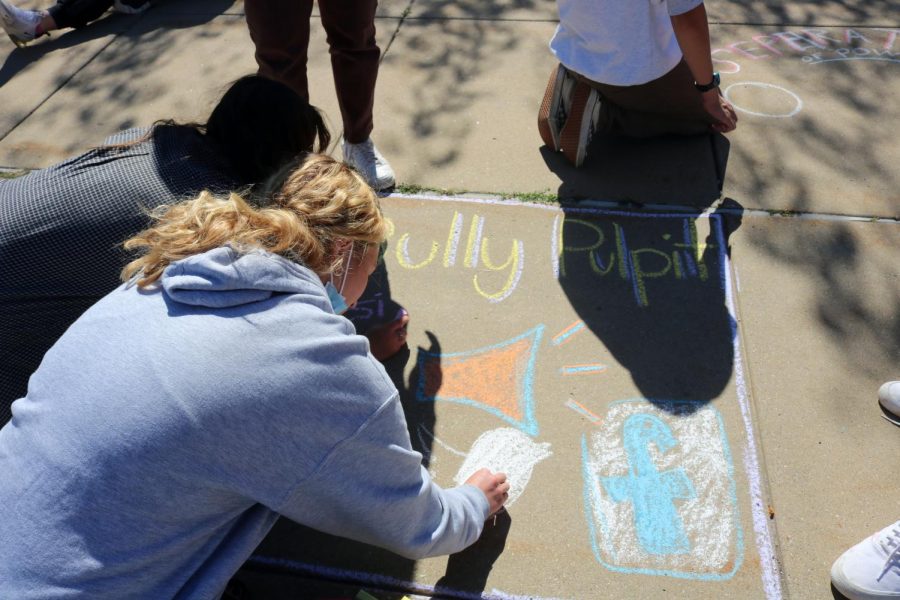Junior Tammy Craven draws on the sidewalk with chalk. On Sept. 29th Mr. Lawrences AP Government class did this for a class project. 