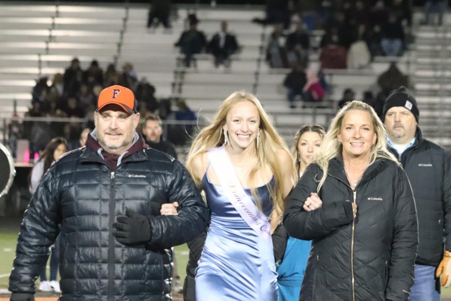 Senior Grace Olsen walking with her parents representing homecoming court on Oct.23.  