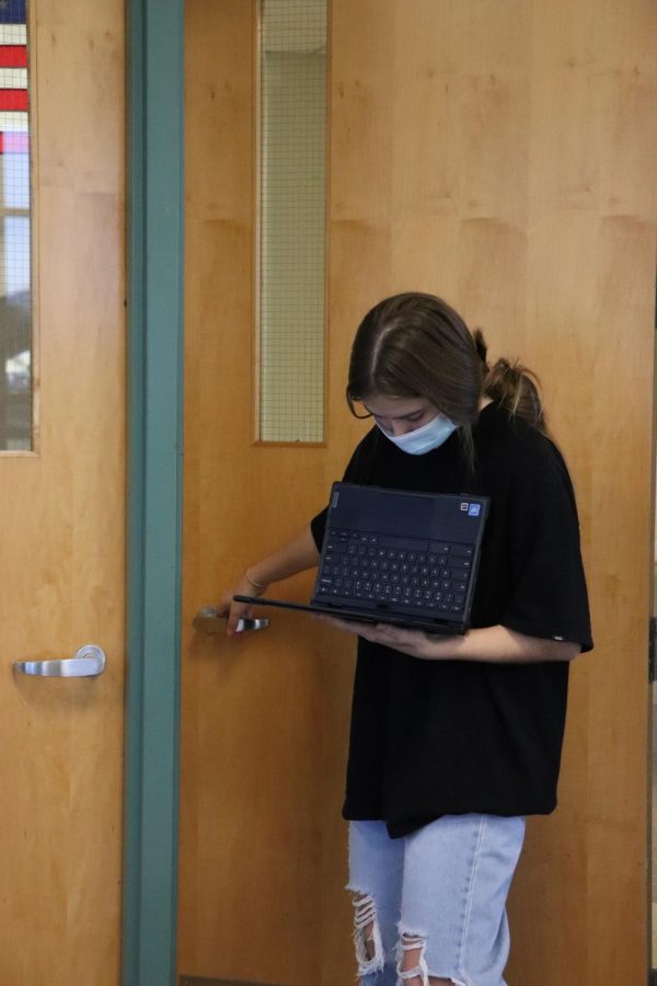 Opening the door, sophomore Michaela Pescarolo, creates sound affects for her groups project. On Dec. 14,  the American Studies class recorded a radio broadcast in 1930s style. 